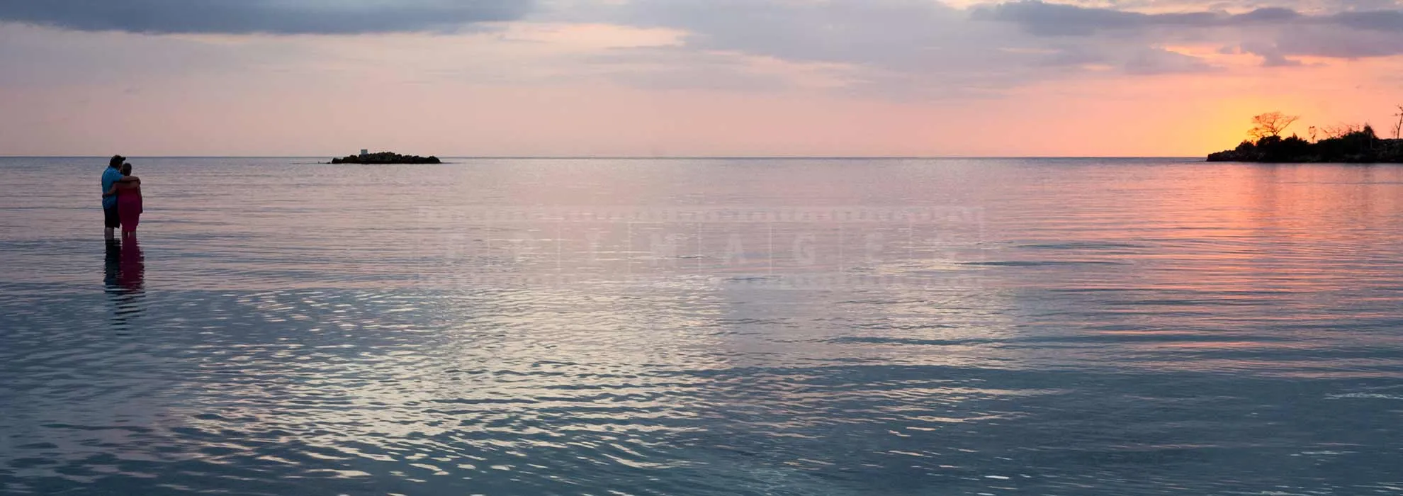 Couple watching gorgeous sunset over the Caribbean sea in Negril Jamaica