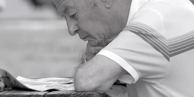 Black and white portrait of an old man reading newspaper