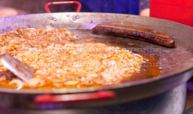 frying pan with onions and a sausage