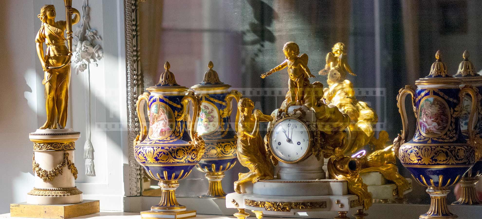 clock in front of a mirror surrounded by two vases