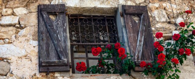 Beautiful medieval window with red roses in Eze Village