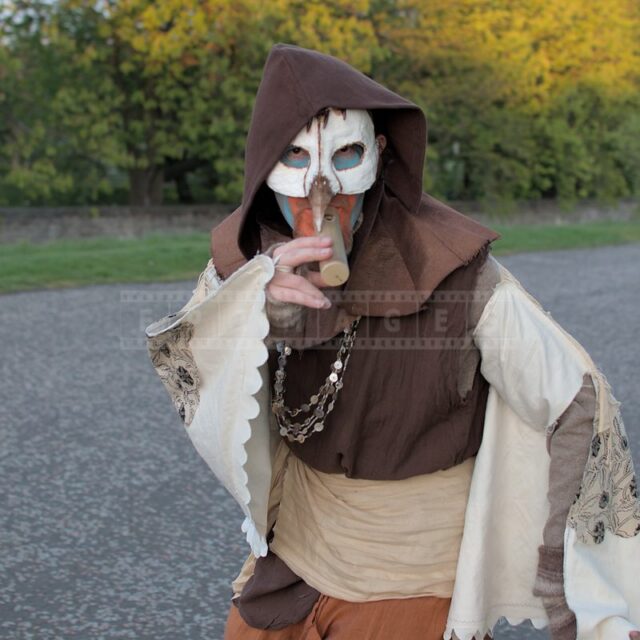Artist in a Bird-like mask and playing old musical instrument
