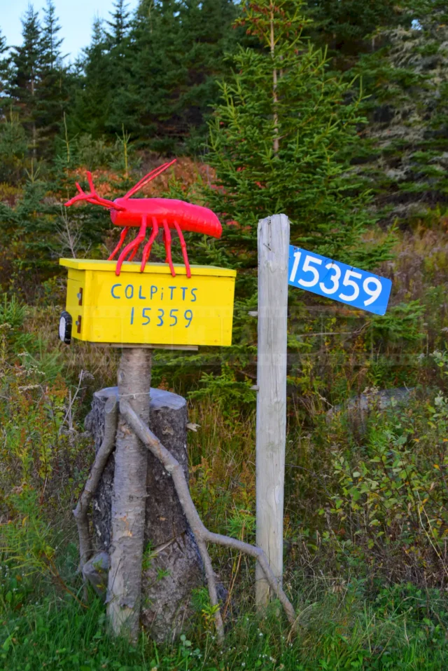 Bright red figure on top of the yellow mailbox, folk art.