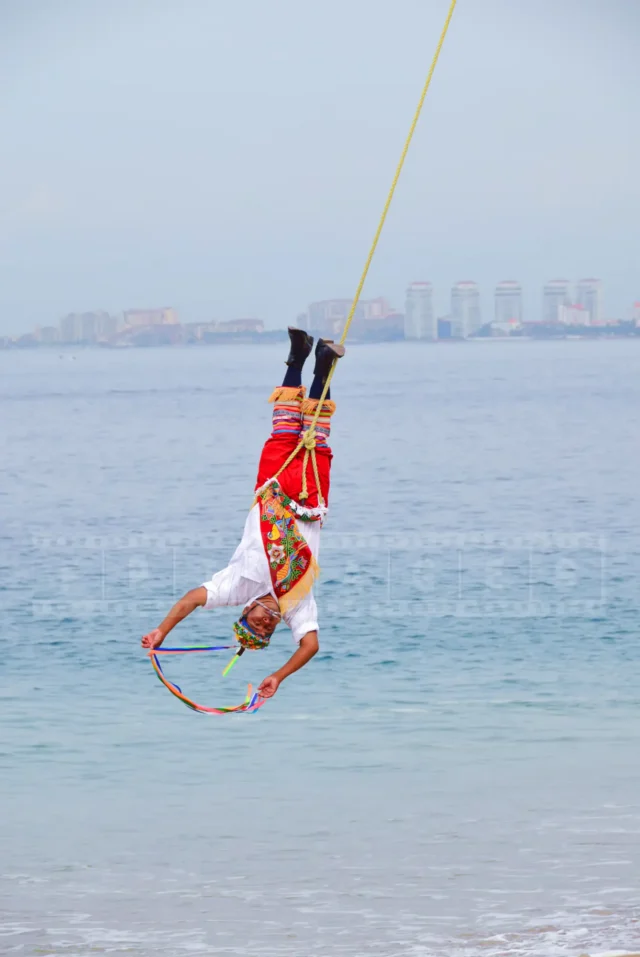 bird-man, papantla flyer is suspended and going around the pole upside-down