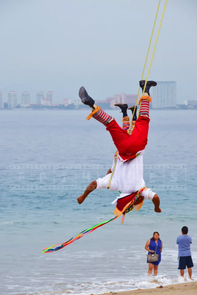 Colorful costumes of the bird-men flying upside down above the sea.