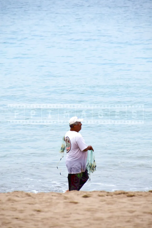 A fisherman walking on the beach