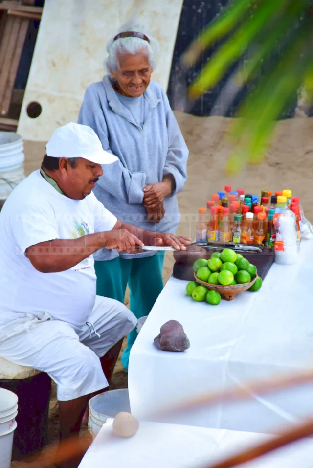 Old Mexican Lady and a man sharpening his knife to prepare fresh oysters