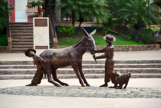 Stubborn donkey and two boys and a dog trying to pull him